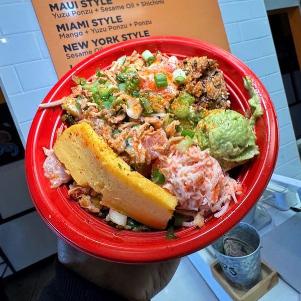 A vibrant Poke Poku bowl with various toppings, including avocado, crab salad, and tamagoyaki.